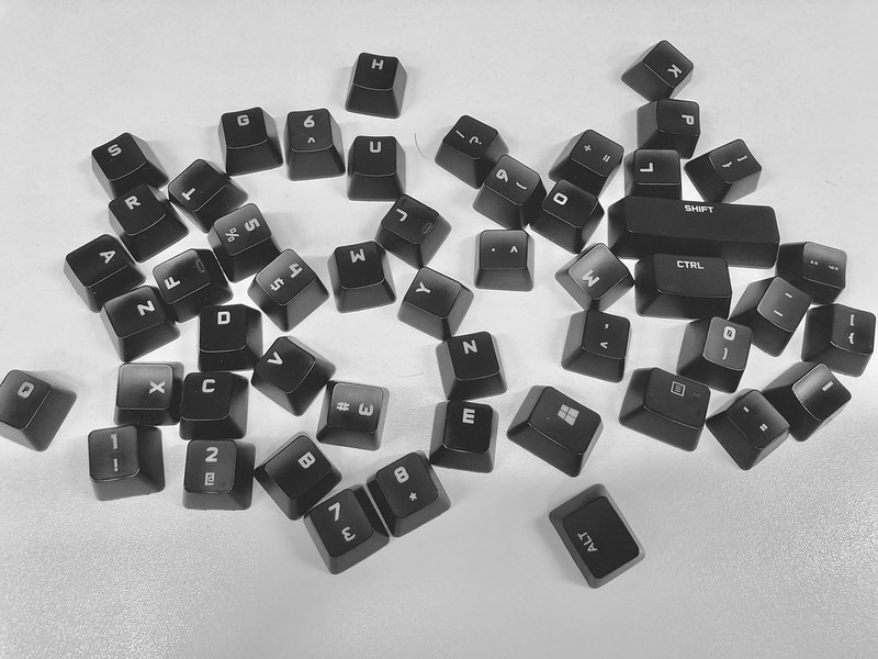 A photo showing the keys from a computer keyboard scattered across a white background